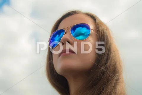 The young woman watch through glasses at the clouds by the blue sky background Stock Photos