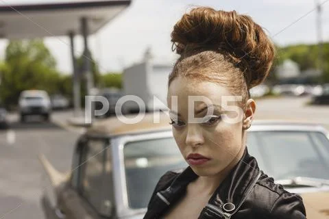 A young woman wearing makeup and a severe expression in a leather jacket. Stock Photos