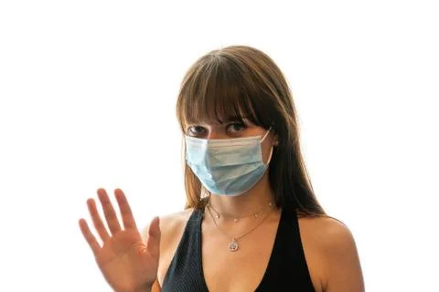 Young woman wearing medical face mask waving at camera Stock Photos