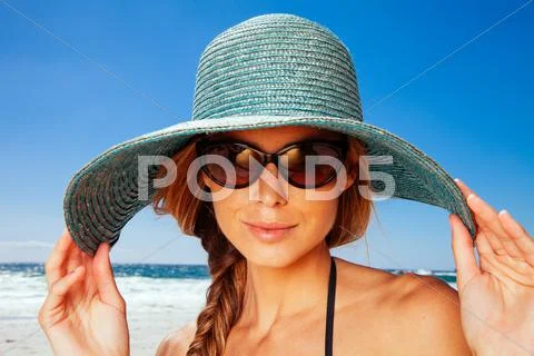 Young Woman Wearing Sun Hat On The Beach