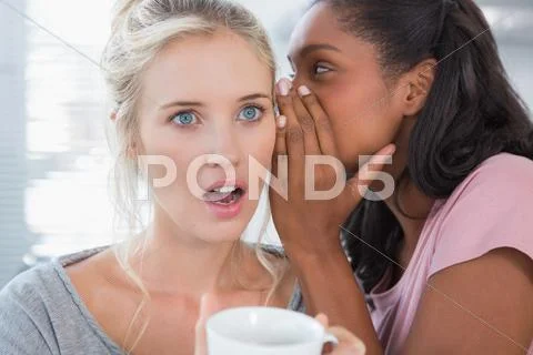 Young woman whispering secret to her friend Stock Photos