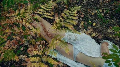 Young woman in white sexy lingerie lying on the ground in the autumn forest. Stock Footage