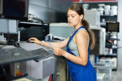 Young woman worker operating computerised machine to mix paint in paint shop Stock Photos