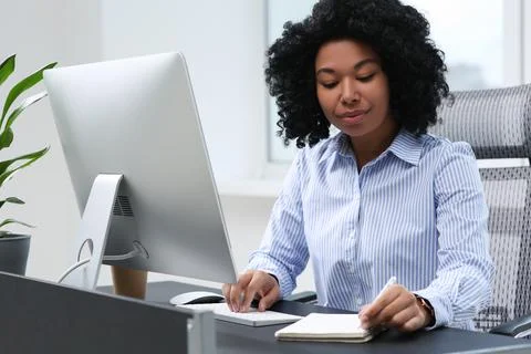 Young woman working on computer at table in office Stock Photos