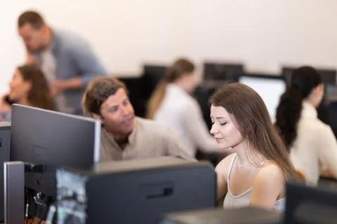 Young woman working on computer talking to man Stock Photos