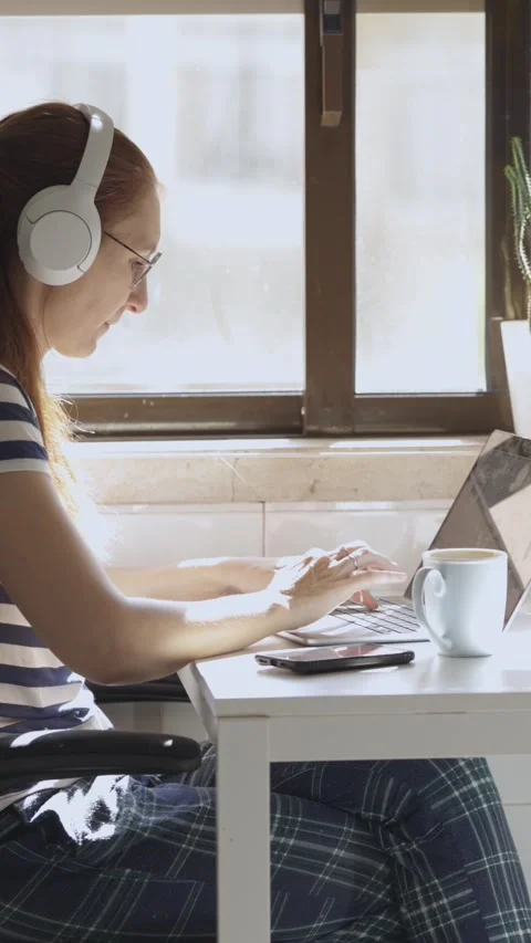 A young woman is working at home at a computer with headphones during breakfast Stock Footage 328295232