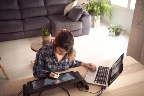 Young woman working from home due to the global pandemic. Illustrator working Stock Photos