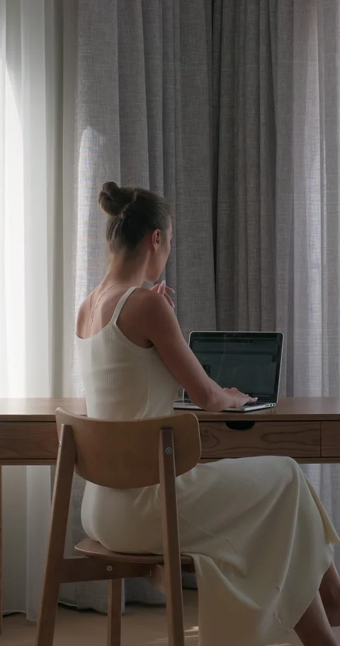 Young woman working on laptop computer sitting at a desk, typing email, browsing Stock Footage 290226080