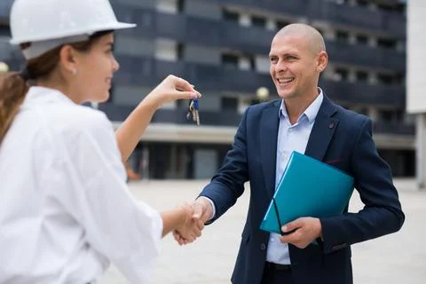 Young woman working as a process engineer hands over the keys to a man customer Stock Photos