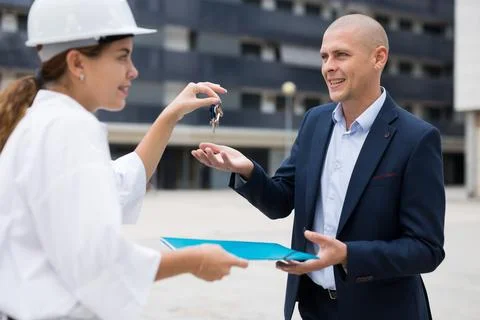 Young woman working as a process engineer hands over the keys to a man customer Stock Photos