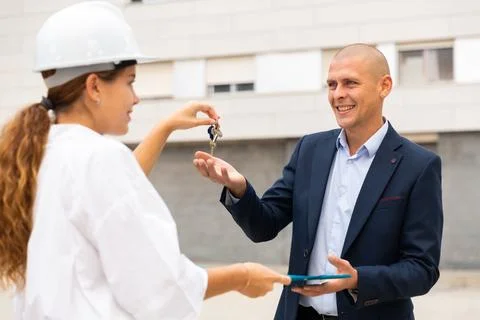 Young woman working as a process engineer hands over the keys to a man customer Stock Photos