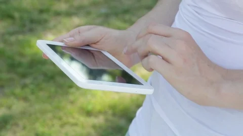 Young woman working on tablet computer with green grass background, outdoor Stock Footage 72346066