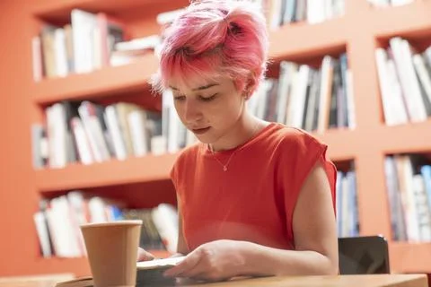 Young woman working while drinking coffee in the office. Generation Z woman.. Stock Photos