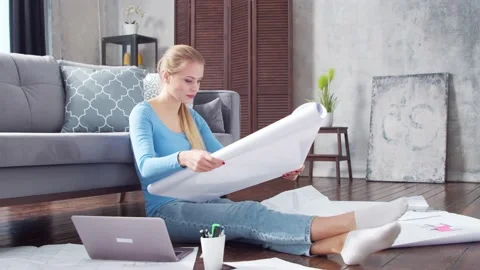 Young woman works with documents using a laptop while sitting on the floor at Stock Footage 169654290
