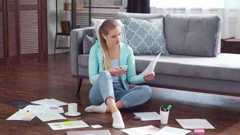 Young woman works with documents using a laptop while sitting on the floor at Stock Footage 170376845