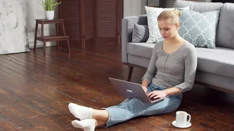 Young woman works with documents using a laptop while sitting on the floor at Stock Footage 170669954