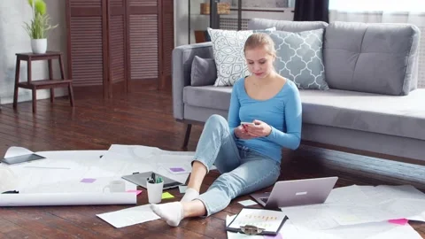 Young woman works with documents using a laptop while sitting on the floor at Stock Footage 171113152