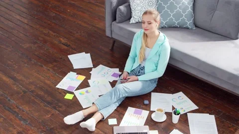 Young woman works with documents using a laptop while sitting on the floor at Stock Footage 171622425