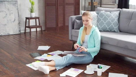 Young woman works with documents using a laptop while sitting on the floor at Stock Footage 171680853