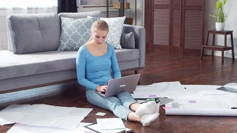 Young woman works with documents using a laptop while sitting on the floor at Stock Footage 171680945