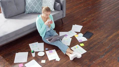 Young woman works with documents using a laptop while sitting on the floor at Stock Footage 171681071