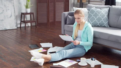 Young woman works with documents using a laptop while sitting on the floor at Stock Footage 171814646