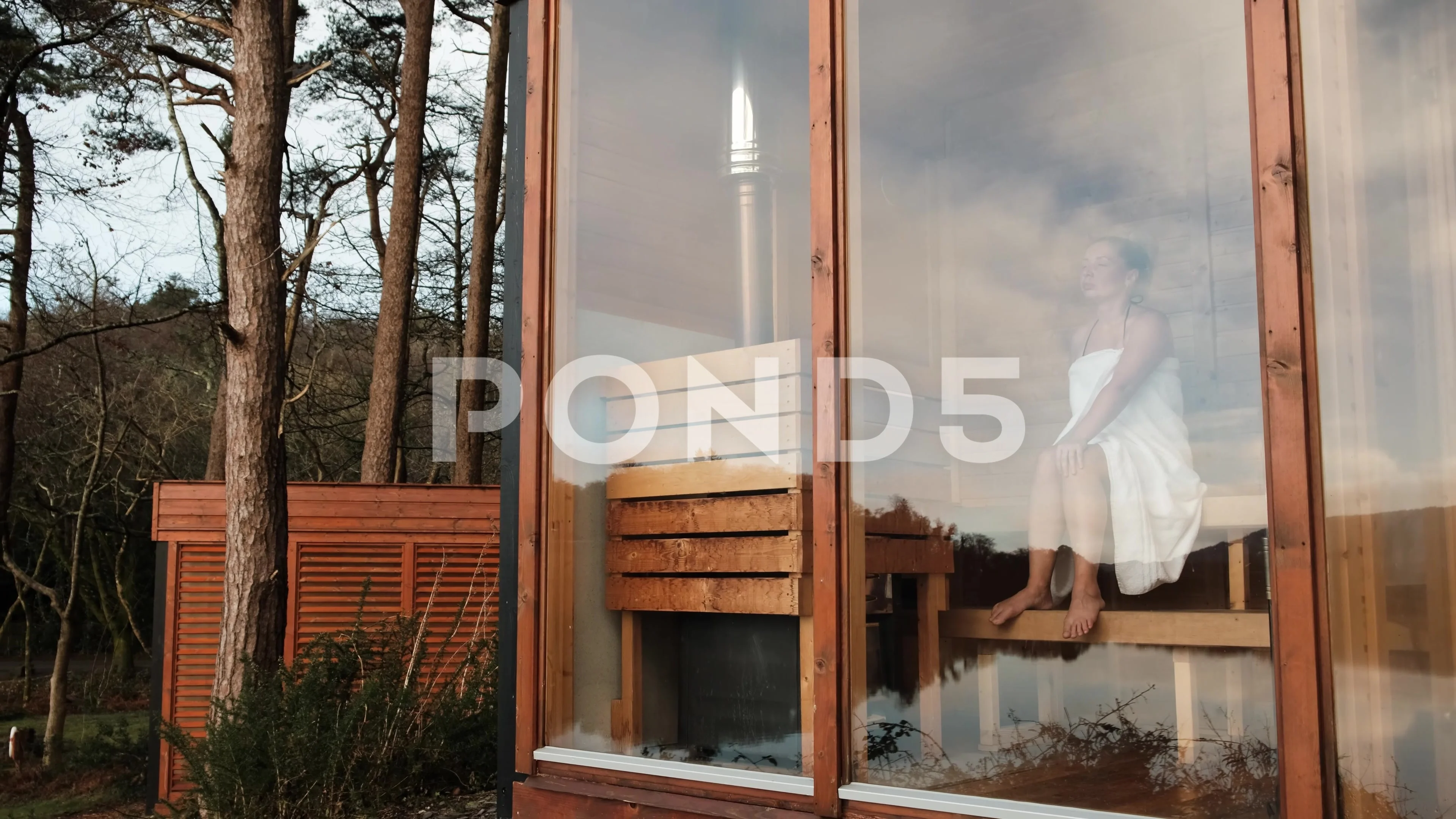 Women Wrapped In Towel Sitting In Sauna Smiling High-Res Stock