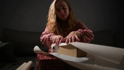Young woman wrapping gift boxes in colorful paper Vidéo 340065472
