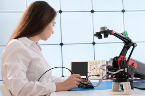A young woman writes an algorithm for the robot arm. Science Research Laborat 写真素材