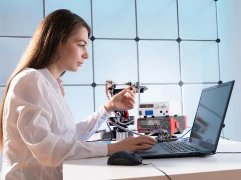 A young woman writes an algorithm for the robot arm. Science Research Laborat 库存照片