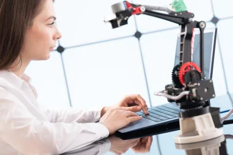 A young woman writes an algorithm for the robot arm. Science Research Laborat Stockfoto's