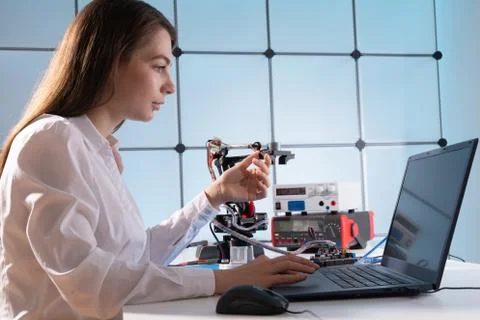 A young woman writes an algorithm for the robot arm. Science Research Laborat 库存照片