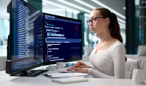 Young Woman Writing Code On Cloud-based Development Terminal At Desk. Stock-Fotos