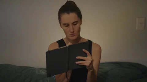 Young Woman Writing in a Journal While Sitting on Her Bed 스톡 동영상 337971308