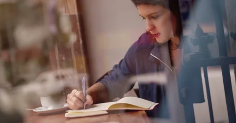Young Woman Writing Journal at Window Seat in Coffee Shop Stock Footage