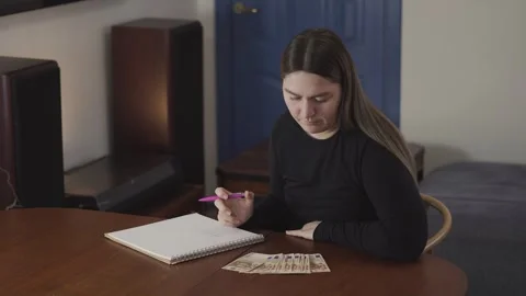 Young woman writing in notebook at table with colored pencils in home interior Stock Footage 333940407