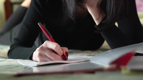 Young woman writing in notebook while lying on bed. Home environment. Stock Footage 297901839