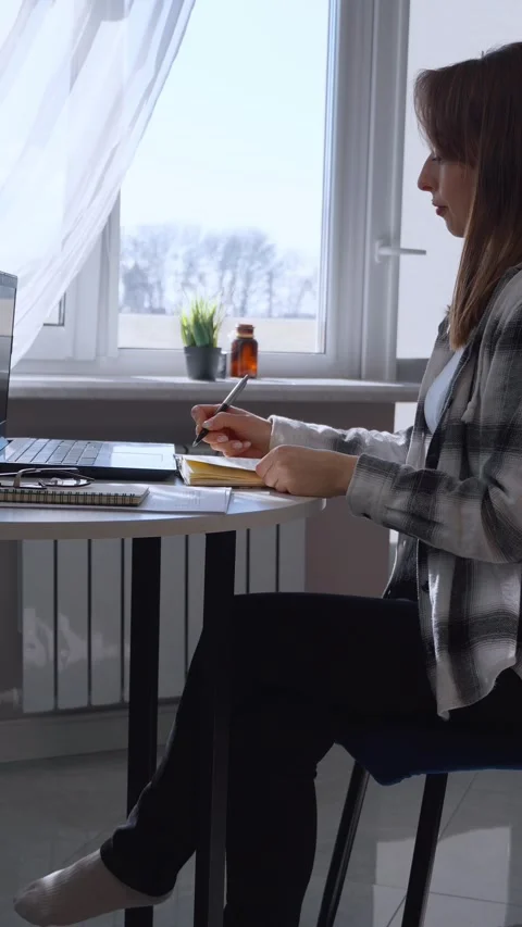 Young woman writing on notepad while working from home Stock Footage 314622447