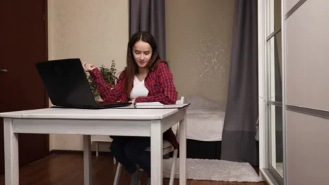 Young Woman Writing Notes in Notebook While Working Remotely on Laptop from.. Stock Footage 307757320