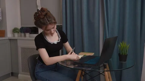 Young woman writing notes while studying at home Stock Footage 311780124