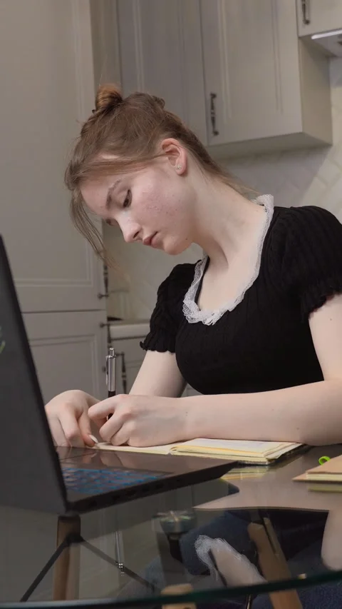 Young woman writing notes while studying on laptop at home Stock Footage 311780826