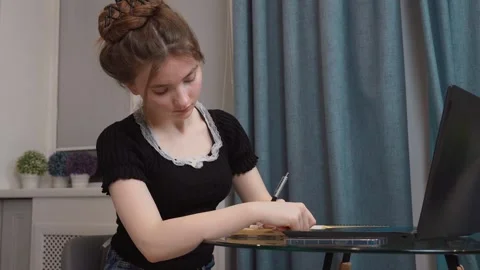 Young woman writing notes while studying at home Stock Footage 311780840