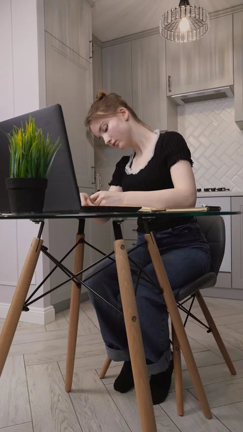 Young woman writing notes while studying on laptop at home Stock Footage 311807668