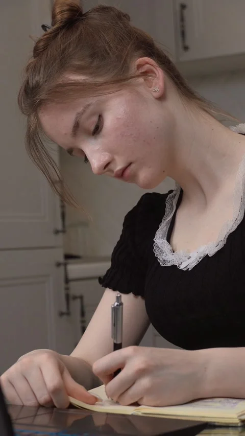 Young woman writing notes while studying on laptop at home Video stock 311808101