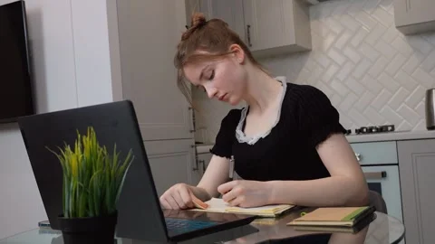 Young woman writing notes while studying on laptop at home Vidéo 311808124