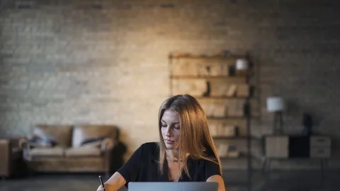 Young woman writing while working with laptop at home Stock Footage 115215459