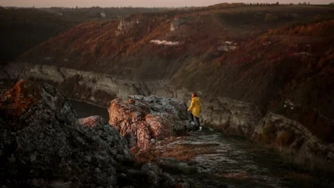 Young woman in yellow jacket running up on top of mountain summit at sunset Stock Footage 221870341