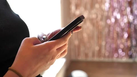 A young woman&amp;#039;s hand using a mobile phone, texting on her smartphone. Stock Footage 335643484