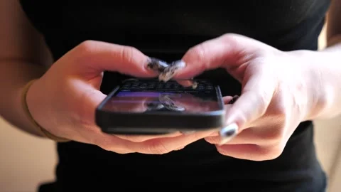 A young woman&amp;#039;s hand using a mobile phone, texting on her smartphone. Stock Footage 335643488