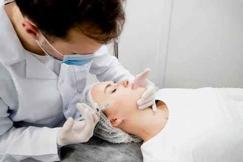 Young woman's getting injections to solve some age-related skin problems and Stock Photos